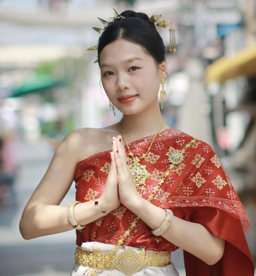 Vrouw in traditionele Thaise kleding die de wai-groet maakt